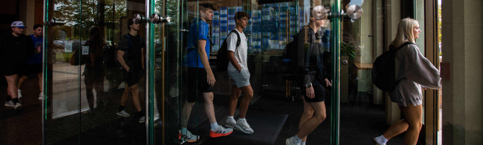 Students walking through the main doors of Seidman, behind glass